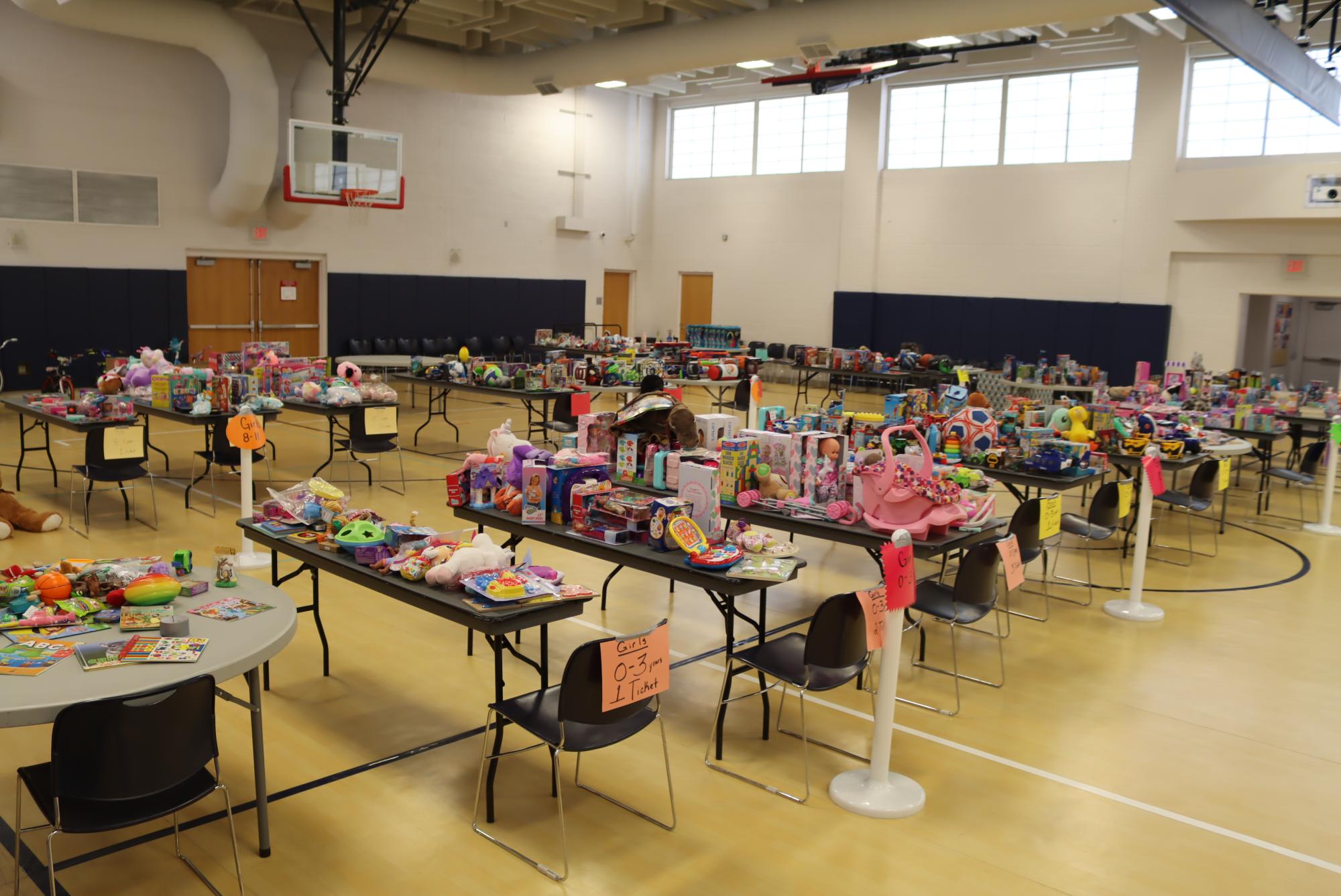 Toys on tables in a gym for a toy drive.