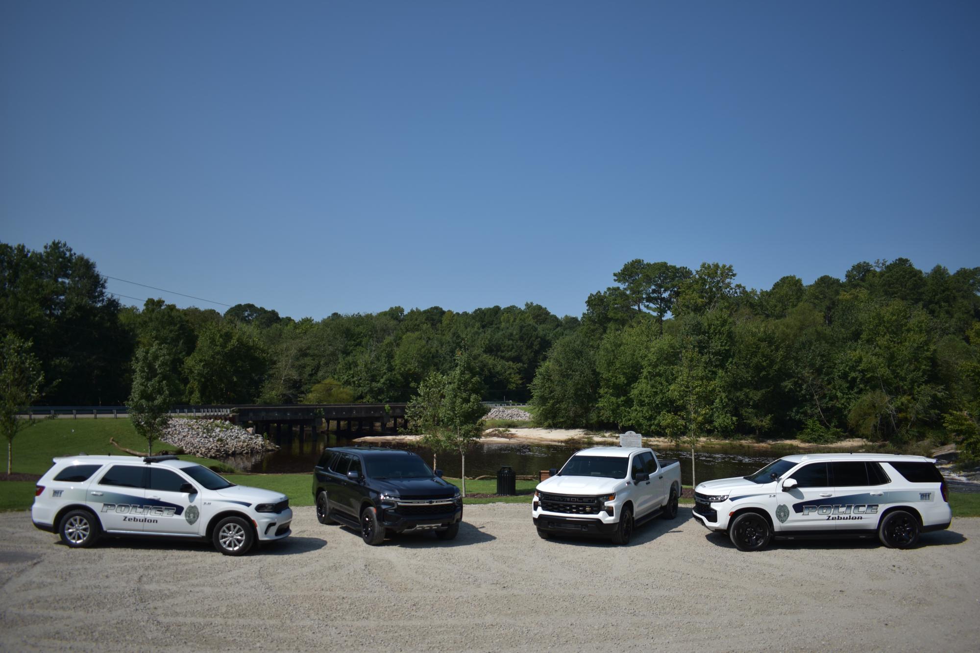 Four ZPD vehicles staged in front of a river.