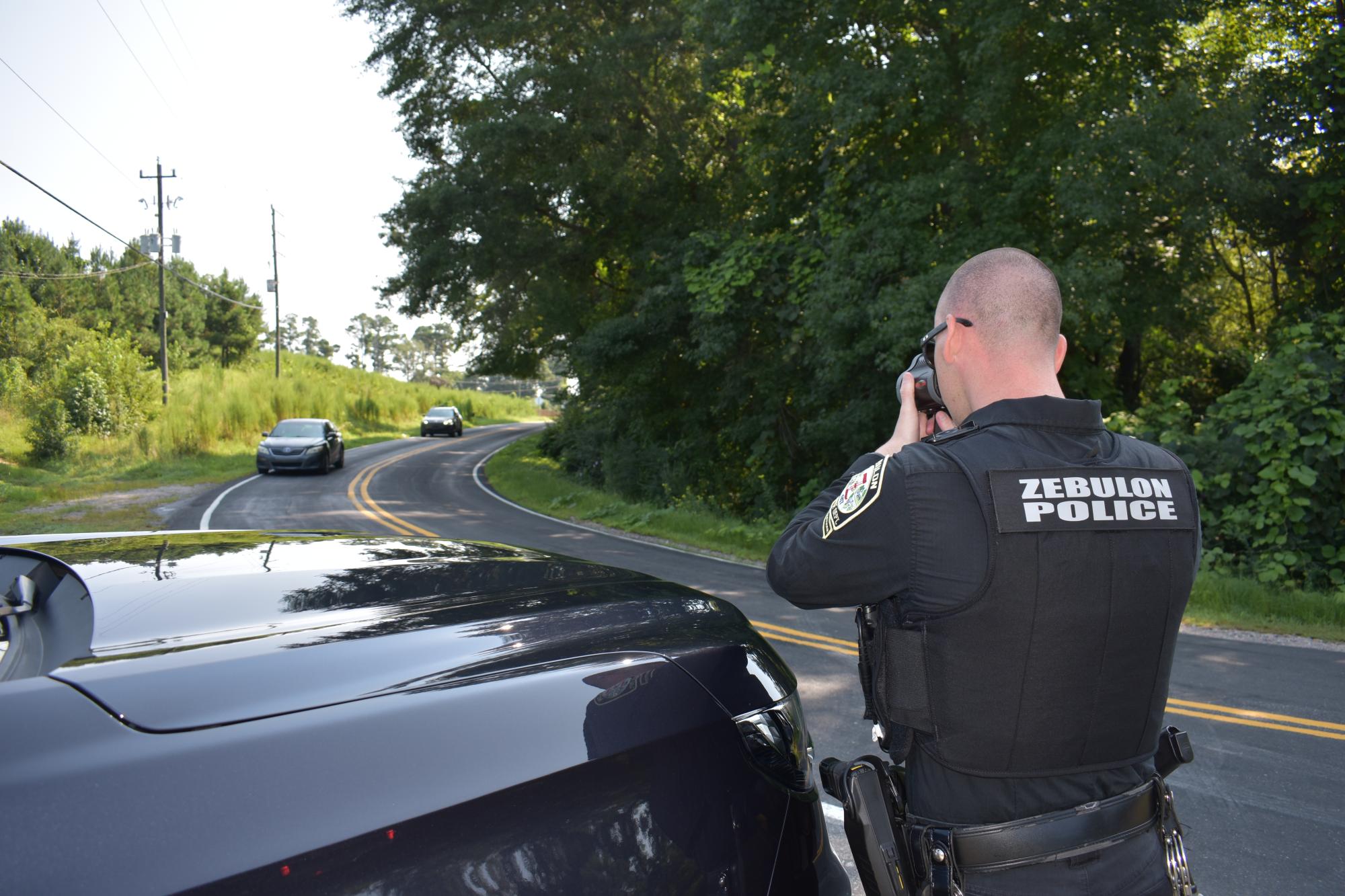 A ZPD officer using a radar to monitor car speed.